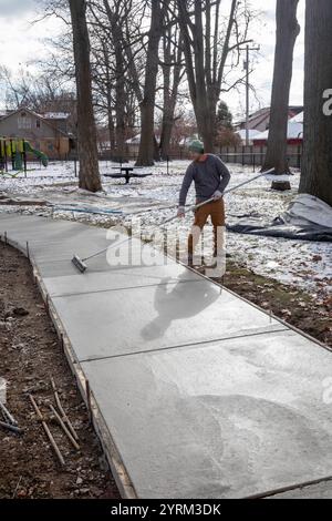 Detroit, Michigan - les ouvriers versent et finissent le béton pour les sentiers pédestres dans Three Mile Park dans le quartier Morningside de Detroit. Banque D'Images