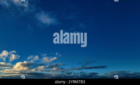 Une vue panoramique d'un ciel bleu principalement clair avec des nuages de cumulus dispersés concentrés au fond. Les nuages sont majoritairement blancs et légers gr Banque D'Images