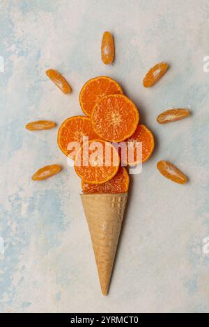 Cône gaufré avec tranches et tranches de mandarine sur fond bleu, vue de dessus Banque D'Images