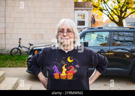 Femme aux cheveux gris posant pour une photographie dans une rue de quartier de la classe ouvrière dans la petite ville du Midwest de Ludington, Michigan, États-Unis. Banque D'Images