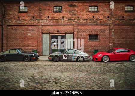 Trois voitures Porsche classiques stationnées devant un bâtiment rustique en briques en Écosse, présentant un mélange de designs vintage et modernes. Banque D'Images