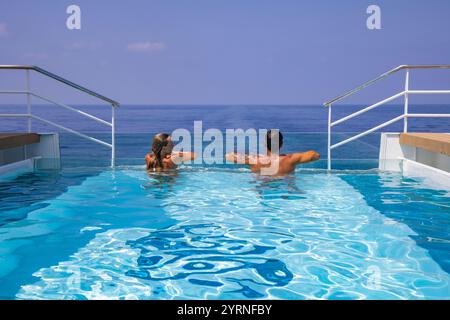 Femme et homme se relaxant au bord de la piscine à débordement du navire de croisière d'expédition SH Diana (Swan Hellenic), en mer, près de l'Arabie Saoudite, moyen-Orient Banque D'Images