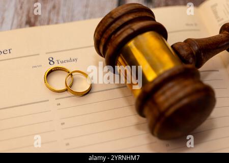Anneaux de mariage et marteau sur le calendrier, symbolisant le divorce, la séparation légale et la fin du mariage. Banque D'Images