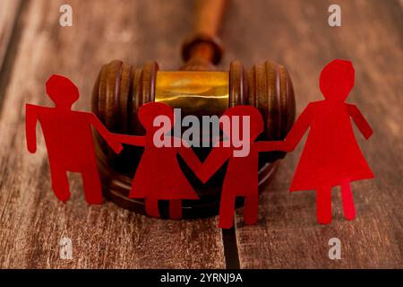 Chaîne familiale en papier rouge devant un marteau. Notions juridiques de garde d'enfants, de divorce et d'adoption. Banque D'Images