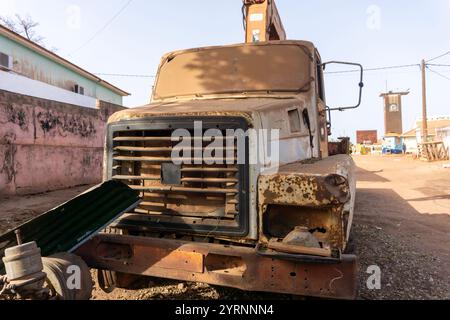 Camion grue abandonné dans African Village. Prise de vue à faible angle d'une grue montée sur camion endommagée ou délabrée. Pare-brise rendu opaque par le sable Banque D'Images
