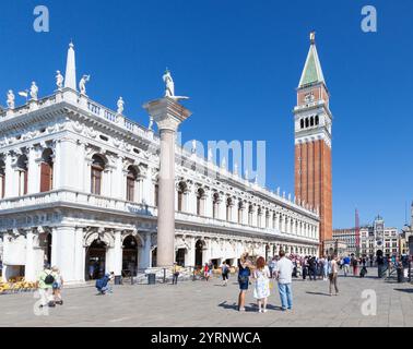 Bibliothèque Marciana et Campanile, Piazetta San Marco, Venise, Italie avec la colonne à St Théodore, Tour de l'horloge en arrière-plan avec des touristes Banque D'Images