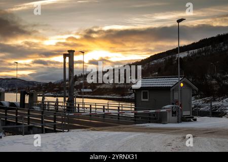 Vide port fermé d'un traject aux petites îles. Montagne avec des arbres et des maisons en arrière-plan. Neige sur la terre. Ciel nuageux avec ensoleillement en t Banque D'Images