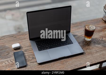 Ordinateur portable avec smartphone, écouteurs et café espresso tonique sur la table en bois vintage dans le café, vue de dessus. Travail à distance et flux de travail créatif. Coworking Banque D'Images