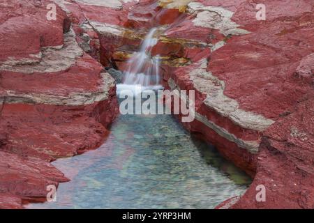 Ruisseau coule à travers la roche riche en fer, Red Rock Canyon, Waterton Lakes National Park, Alberta, Canada Banque D'Images