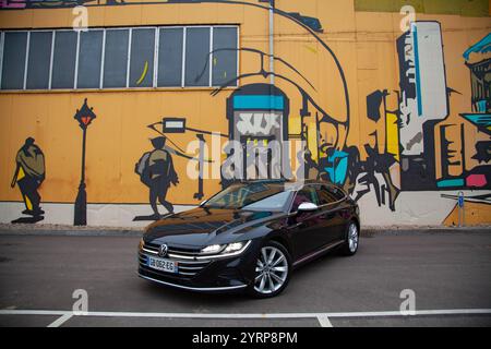 Vilnius, Lituanie - 10-11-2024 - Volkswagen Arteon face au mur de graffitis lumineux, vue de face Banque D'Images