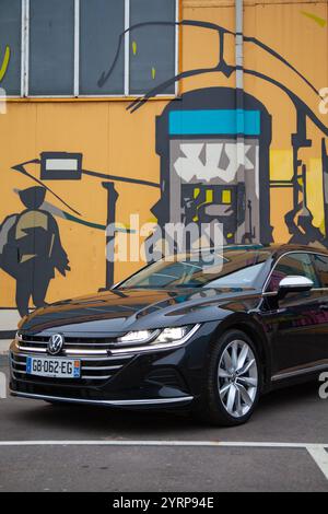 Vilnius, Lituanie - 10-11-2024 - Volkswagen Arteon face au mur de graffitis lumineux, vue de face Banque D'Images