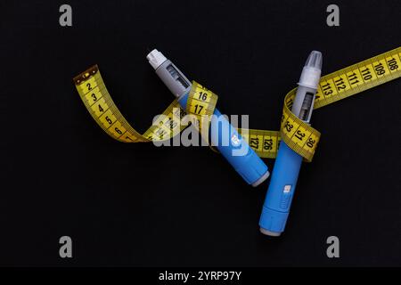 Injection de drogue ozempic avec un ruban à mesurer jaune sur fond noir. Stylo injecteur d’insuline Ozempic ou stylo cartouche d’insuline pour diabétiques. Médical Banque D'Images