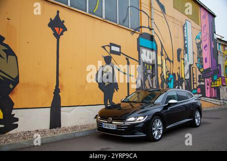 Vilnius, Lituanie - 10-11-2024 - Volkswagen Arteon face au mur de graffitis lumineux, vue de face Banque D'Images