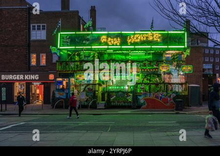 Southampton, Royaume-Uni. 4 décembre 2024. Les gens marchent devant la partie de divertissement de Fun House illuminé vert vif du marché de Noël de Southampton (géré par S&d Leisure) cette année. L'attraction est située le long de Bargate Street. Banque D'Images