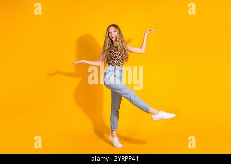 Jeune femme joyeuse dans le haut élégant léopard pose sur fond jaune vif, exprimant le bonheur et le charme. Banque D'Images