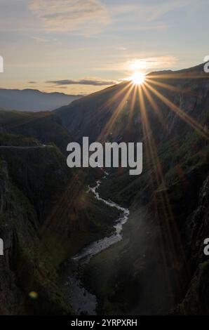 Coucher de soleil à couper le souffle sur une vallée profonde avec une rivière sinueuse, entourée de falaises abruptes et de verdure luxuriante. Banque D'Images
