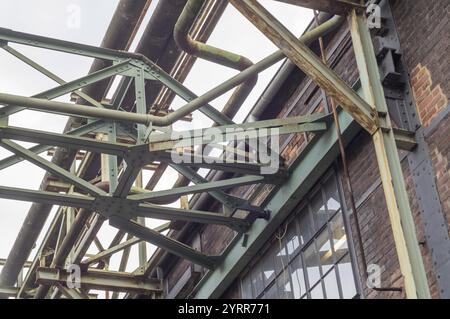 Ossature métallique supportant des pipelines sur un vieux mur de briques dans un environnement industriel Banque D'Images