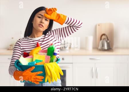 Femme asiatique travaillant dur avec busket plein de fournitures de nettoyage Banque D'Images