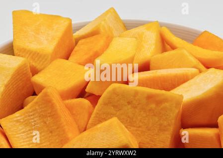 Une vue rapprochée de morceaux de citrouille coupés en dés dans un bol blanc. Banque D'Images