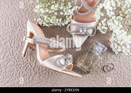 Vie morte délicate de mariage des détails de mariage. chaussures en satin avec un noeud de strass, parfum, bagues, brins de gypsophila blanc. vue de dessus Banque D'Images