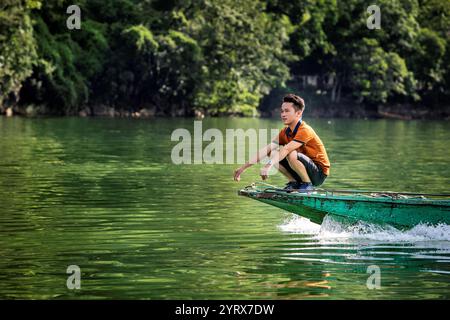 Un homme assis sur la proue d'un bateau voyageant sur le lac Ba Be dans le parc national de Ba Be dans la province de bac Kan, au Vietnam Banque D'Images