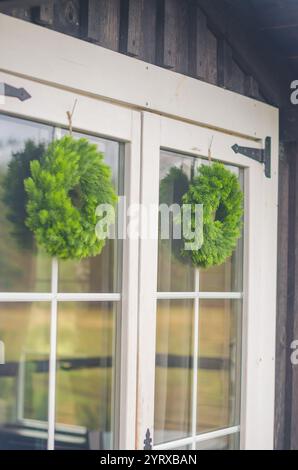Fenêtre en bois blanc rustique ornée de couronnes vertes fraîches pour un décor de vacances. Photo de haute qualité Banque D'Images