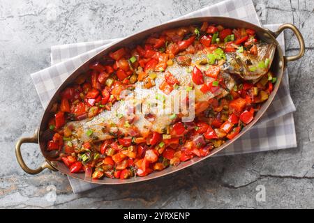 Poisson de mer blanc dans son propre jus cuit avec des légumes de saison gros plan dans une poêle sur la table. Vue horizontale de dessus Banque D'Images