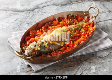 Poisson de mer blanc dans son propre jus cuit avec des légumes de saison gros plan dans une poêle sur la table. Horizontal Banque D'Images