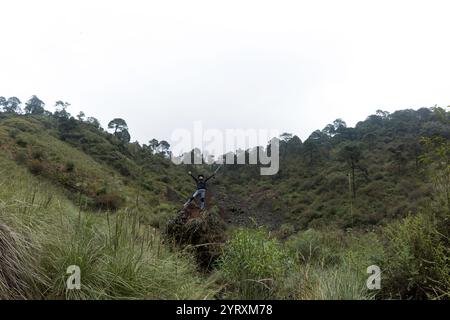 Une personne se dresse triomphalement sur un éperon rocheux dans la vallée pittoresque du volcan el Ajusco, entourée d'une végétation luxuriante et d'une beauté naturelle. Le randonneur, w Banque D'Images