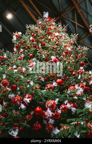 3-12-2024 Zurich, Suisse. Grand sapin de Noël à l'intérieur de la gare principale de Zurich décoré de boules de chocolat Lindt rouges. Gros plan, regardant vers le haut plan, non Banque D'Images