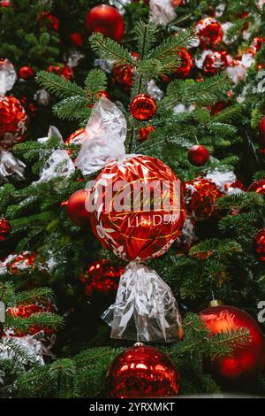3-12-2024 Zurich, Suisse. Grand sapin de Noël à l'intérieur de la gare principale de Zurich décoré de boules de chocolat Lindt rouges. Gros plan, regardant vers le haut plan, non Banque D'Images