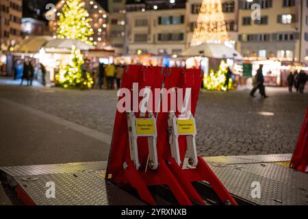3-12-2024 Zurich, Suisse. De grandes barrières d'atténuation rouges et pliables pour véhicules mobiles près de l'entrée du marché de Noël, tard dans la soirée. Banque D'Images