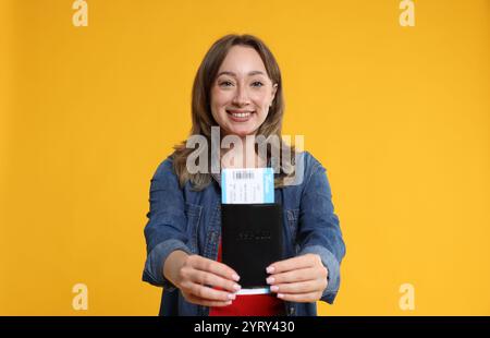 Voyageur heureux avec passeport et billet sur fond jaune Banque D'Images