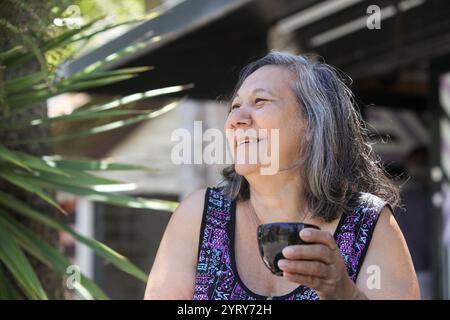 femme latine senior buvant du café ou du thé à l'extérieur le jour ensoleillé d'été Banque D'Images