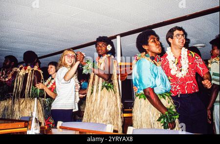 À bord du bateau de croisière Blue Lagoon Cruises aux Fidji, photo d'archives de 1991. Les villageois fidjiens locaux portant des jupes en herbe divertissant les invités à bord du bateau dans la soirée avec un Meke, ou spectacle de danse traditionnelle. Banque D'Images