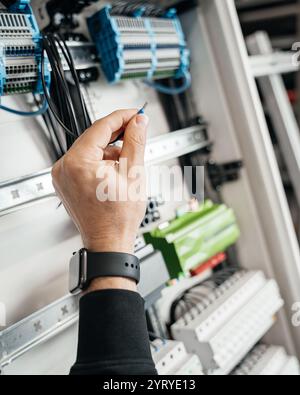 Gros plan d'un fil connecté dans un boîtier électrique de maison intelligente. L'image montre des détails de câblage complexes, soigneusement organisés dans la boîte Banque D'Images