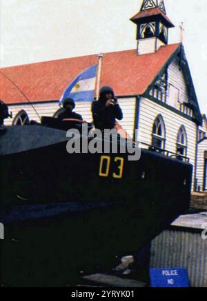 Le drapeau argentin flotte à côté d'un véhicule blindé à Port Stanley après que les forces argentines ont capturé les Malouines en 1982 Banque D'Images