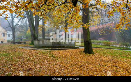 Une belle scène automnale de la fontaine en face du château de Cesky Krumlov, entouré d'arbres aux feuilles dorées, mêlant nature et archit historique Banque D'Images