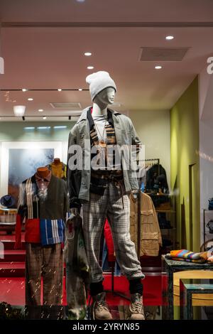 Mannequin masculin dans l'affichage de fenêtre en verre de magasin habillé décontracté automne - hiver vêtements élégants, scène de nuit. Banque D'Images