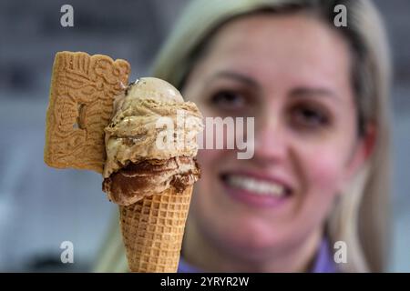 Trèves, Allemagne. 04th Dec, 2024. La propriétaire d'un glacier, Svetlana Novoselska, présente une glace spéculoos sur une boule de tiramisu pendant la saison de l'Avent. Son magasin reste également ouvert en hiver, proposant gaufres, crêpes, gâteaux et boissons chaudes. Crédit : Harald Tittel/dpa/Alamy Live News Banque D'Images