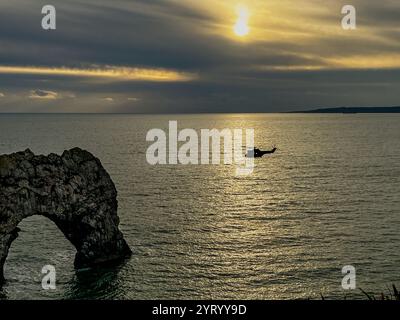 Vol du soir. Un hélicoptère de la RAF Puma passe par Durdle Door, une arche calcaire, sur la côte jurassique dans le Dorset, au Royaume-Uni Banque D'Images