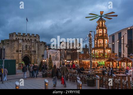 Southampton, Royaume-Uni. 4 décembre 2024. Les gens marchent le long de Southampton Precinct par une journée froide en hiver, où le marché de Noël allemand traditionnel annuel a lieu. Sur la photo, la pyramide de Noël illuminée avec l'historique Southampton Bargate en arrière-plan. Banque D'Images