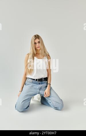 Une jeune femme aux longs cheveux blonds pose élégamment dans un studio chic. Banque D'Images