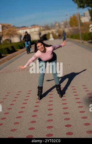 La jeune femme aime le roller dans un parc de la ville, faisant preuve d'équilibre et de liberté Banque D'Images