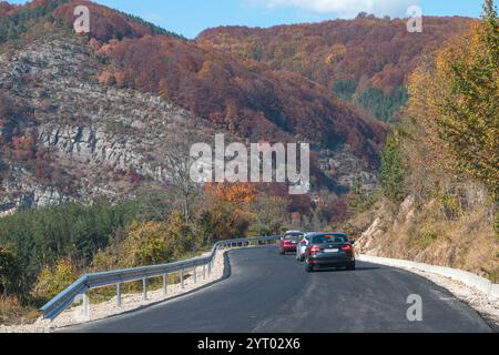 Route de montagne à travers le paysage d'automne pittoresque de la province du Montana, Bulgarie, avec le feuillage d'automne vibrant et les voitures voyageant le long du ro nouvellement pavé Banque D'Images