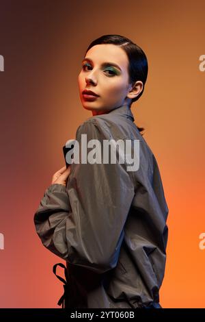 Une jeune femme à la mode présente sa tenue tendance sur un fond dégradé coloré. Banque D'Images