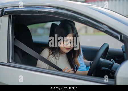 Une jeune femme sur le siège du conducteur, réglage des commandes lorsque la ceinture de sécurité est bouclée Banque D'Images