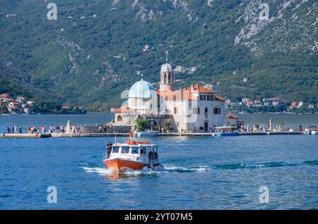 Vue de l'église de l'île appelée 'notre Dame des rochers' situé sur la baie de Kotor au large de la côte de Perast, avec bateau au premier plan, Monténégro, Europe. Banque D'Images