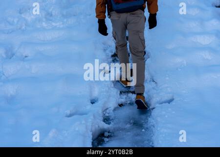 jambes d'homme sans visage marchant le long d'un chemin glacé en hiver après les chutes de neige parmi les neiges Banque D'Images
