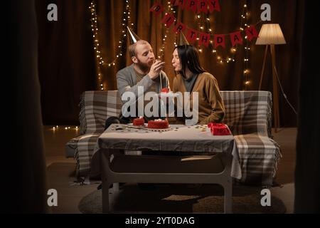 Anniversaire de la femme. mari avec gâteau d'anniversaire nourrissant sa femme. Célébration de l'anniversaire. couple est à la maison célébrant l'anniversaire avec gâteau Banque D'Images